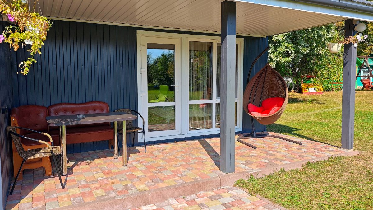 Фиолетовый домик-студия. На террасе качели, стол и стулья